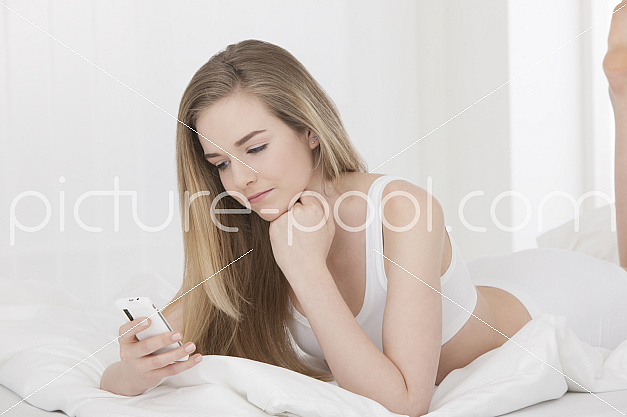 Maedchen im Bett mit Handy
