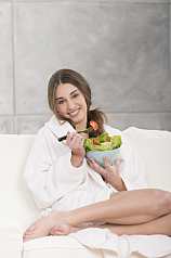 junge Frau isst Salat auf dem Sofa 