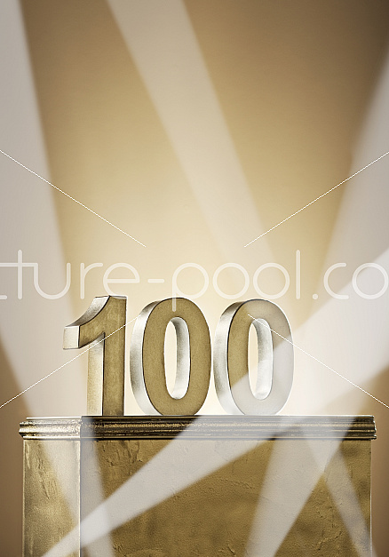 Jubiläumszahl 100 auf goldenem Podest mit Scheinwerfern Jubiläumszahl 100 auf goldenem Podest mit Scheinwerfern