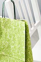 grüne Papiertüte hängt über Stuhllehne