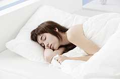 Junge asiatische Frau schläft im Bett zugedeckt