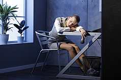 Frau schläft bei Büroarbeit ein 