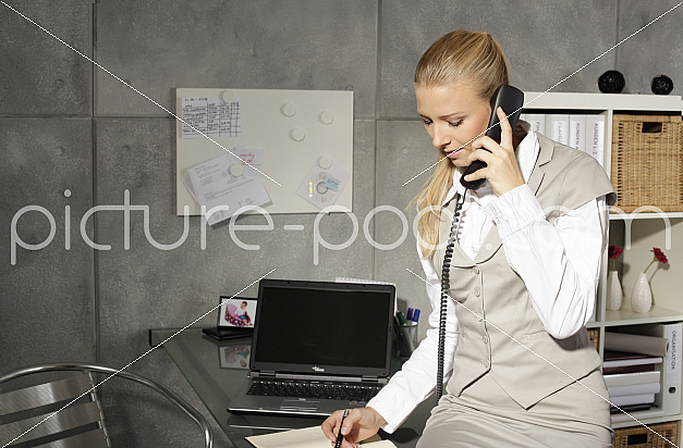 junge Businessfrau telefoniert und macht sich Notizen