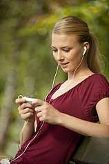 junge Frau sitzt auf Parkbank und hört Musik