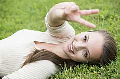 junge Frau macht Handgesten und liegt im Gras