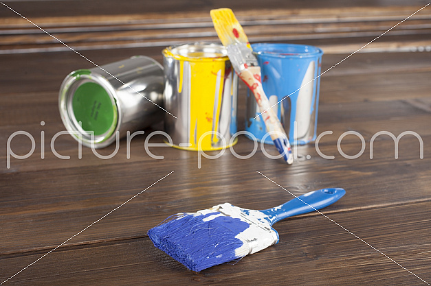 Pinsel mit blauer Farbe vor Malutensilien Pinsel mit blauer Farbe vor Malutensilien