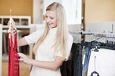 Junge blonde Frau beim Klamotten shoppen