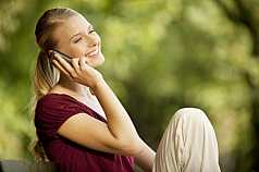 junge Frau sitzt auf Parkbank und telefoniert mit dem Handy