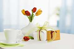 Zwei Geschenke mit Tulpen an Frühstückstisch arrangiert