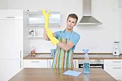 junger Mann putzt Küche