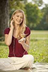 junge Frau hört Musik im Park mit einem MP3 Player
