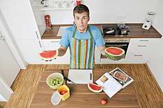 Mann in der Küche hält Wassermelone 