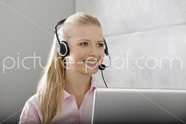 junge Frau mit Laptop und Headset