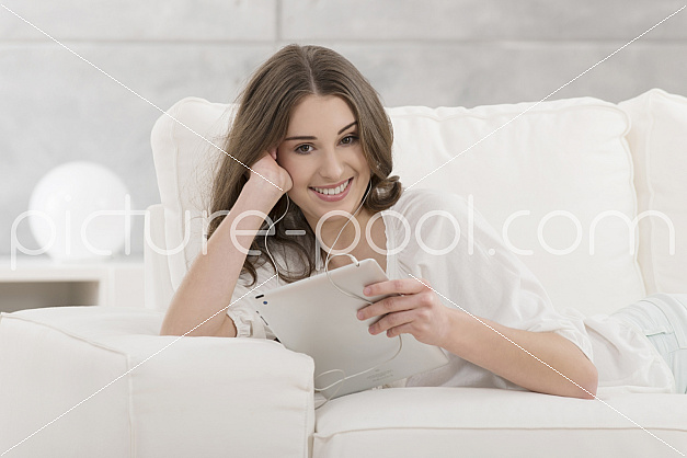 junge Frau mit Ohrenstöpseln und Tablet 